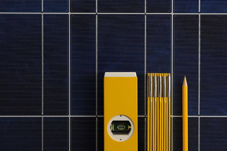 Zollstock, Wasserwaage und Bleistift liegen auf einem Solarmodul