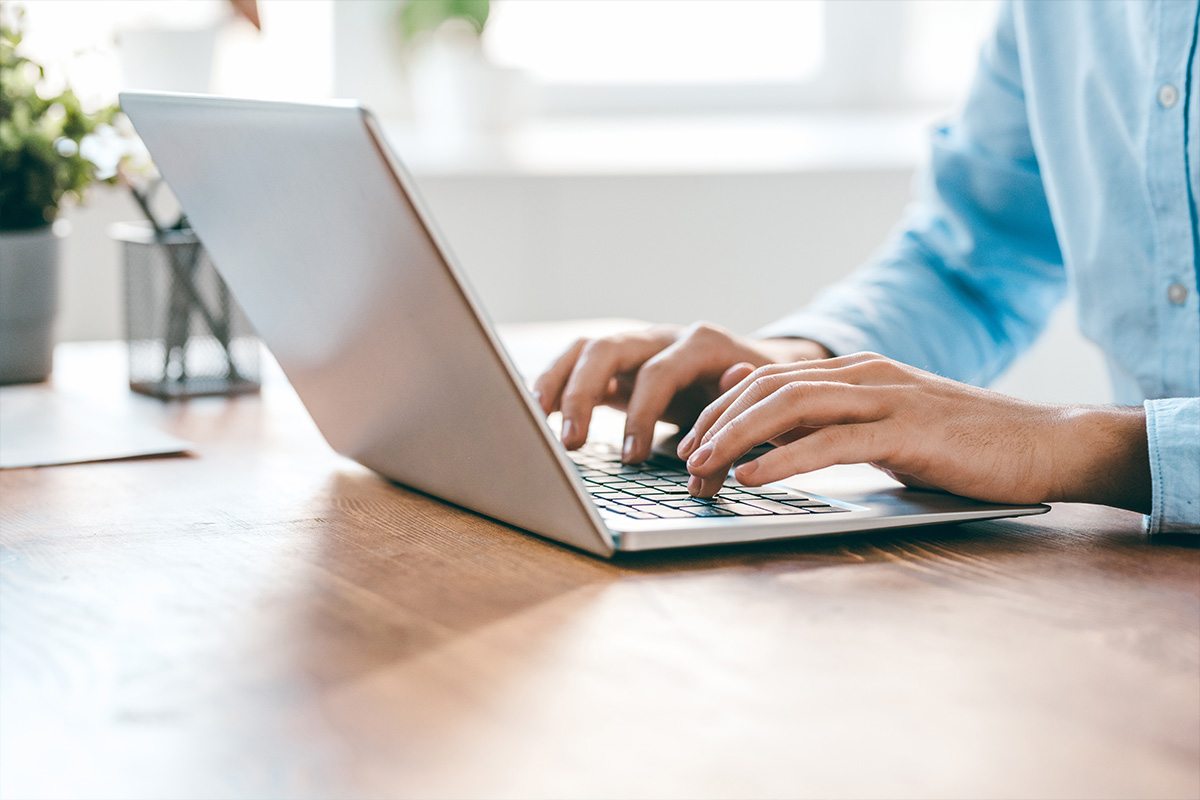 Person tippt auf einem Laptop