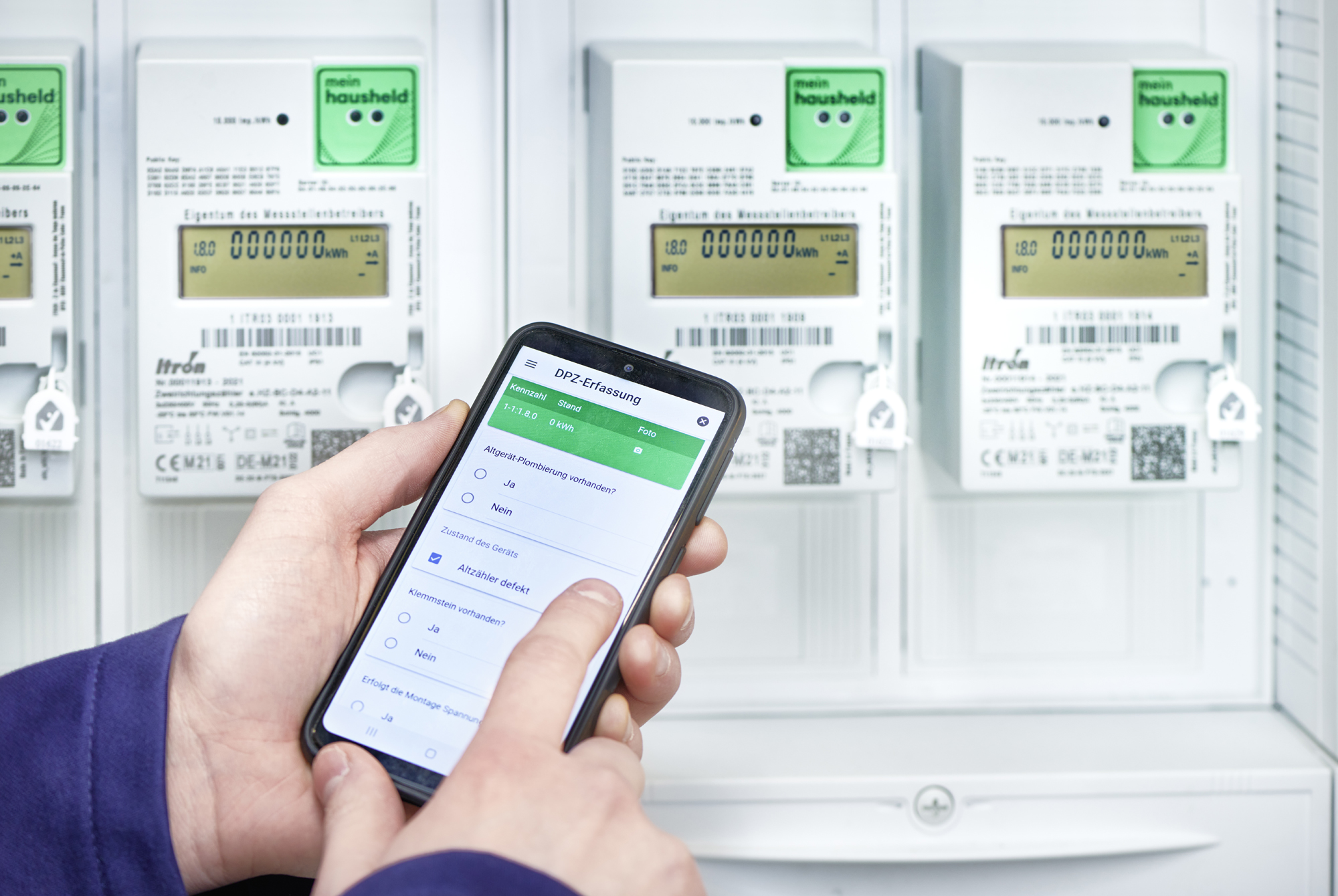 echniker erfasst Smart-Meter-Daten digital über eine App auf dem Smartphone vor einem Zählerschrank mit modernen Stromzählern.
