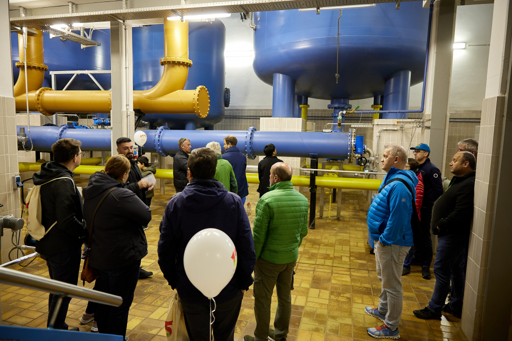 Personen im Inneren des Dachauer Wasserkraftwerks, Tanks und Leitungen im Hintergrund